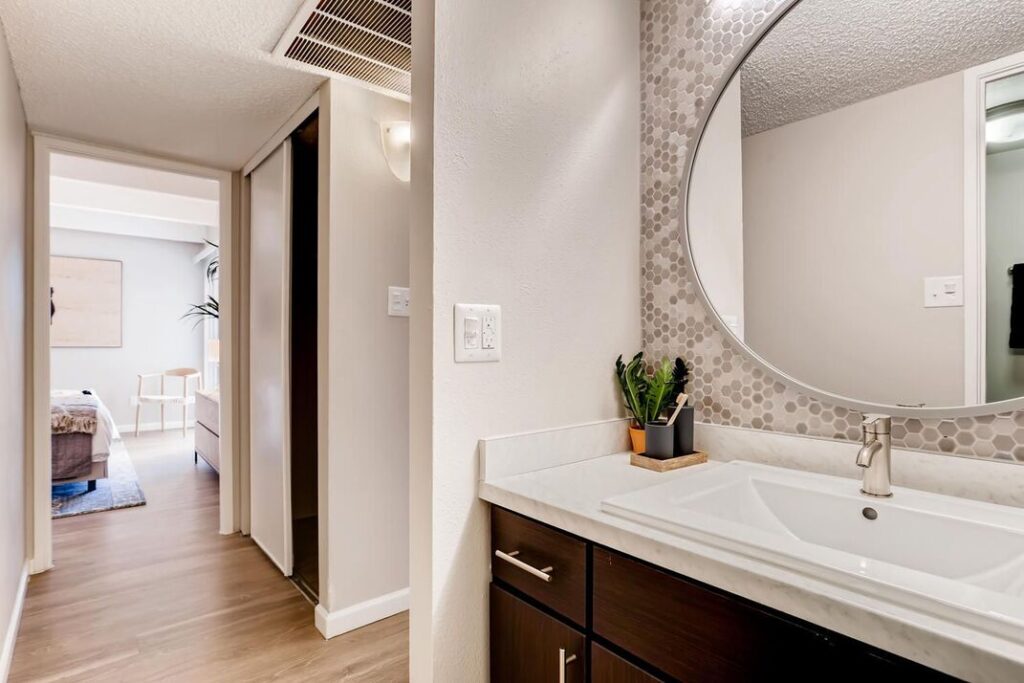 large bathroom with circle mirror and entrance to bedroom