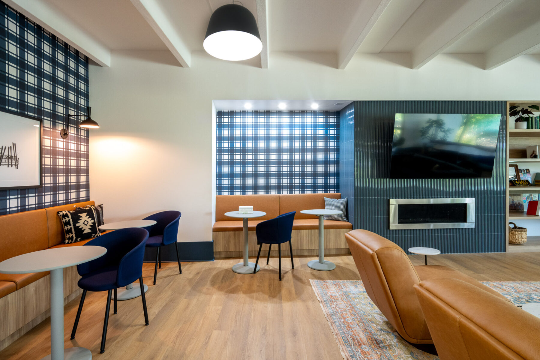indoor community space with booths, tables and chairs next to television and fireplace
