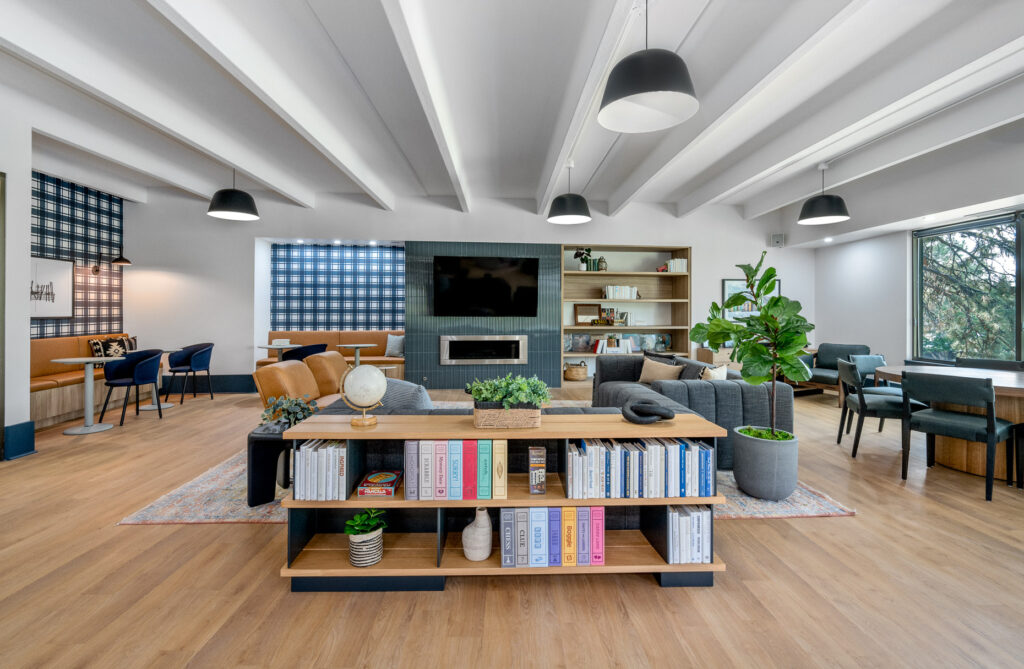 Elm at Panorama clubhouse entry seating space with sofas and armchair seating in a room with overhead and natural lighting with a television and fireplace
